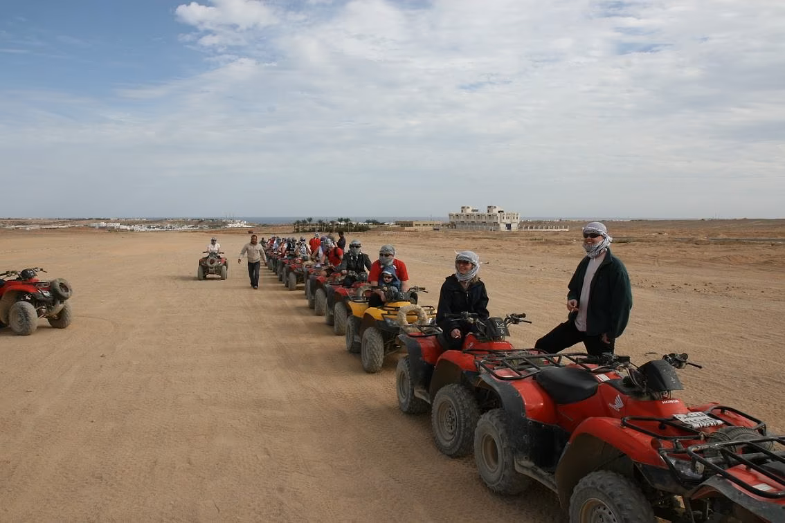 Een rij rode en gele quads met deelnemers met hoofddoeken in de woestijn bij Hurghada