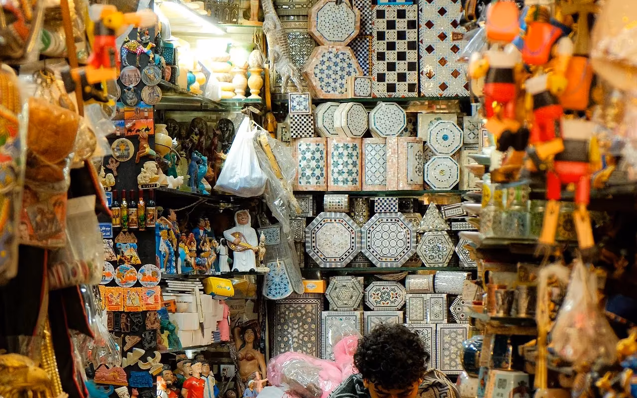 Een kraam vol aardewerk, lampen en souvenirs in een bazaar met een verkoper tussen de waar