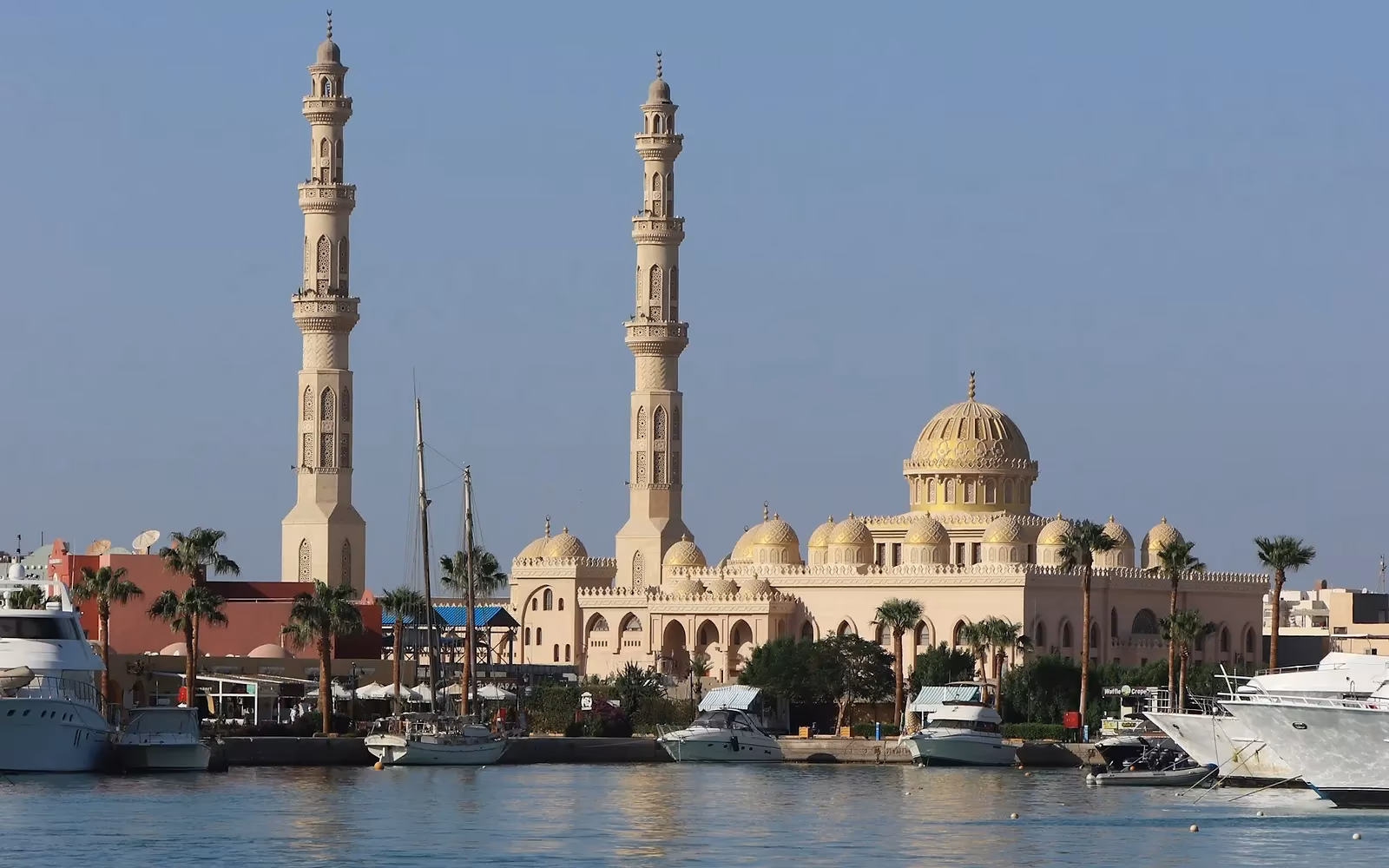 De witte El Mina-moskee met twee hoge minaretten en koepels aan het water van de haven van Hurghada