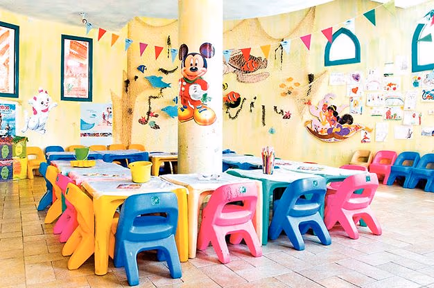 Ruimte van de kidsclub Kids Planet met kleurige kinderstoeltjes en tafels, vlaggetjes, visnetten en tekenfilmfiguren op de muren in Sentido Mamlouk Palace in Hurghada