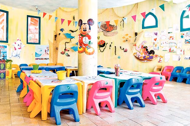Ruimte van de kidsclub Kids Planet met kleurige kinderstoeltjes en tafels, vlaggetjes, visnetten en tekenfilmfiguren op de muren in Sentido Mamlouk Palace in Hurghada