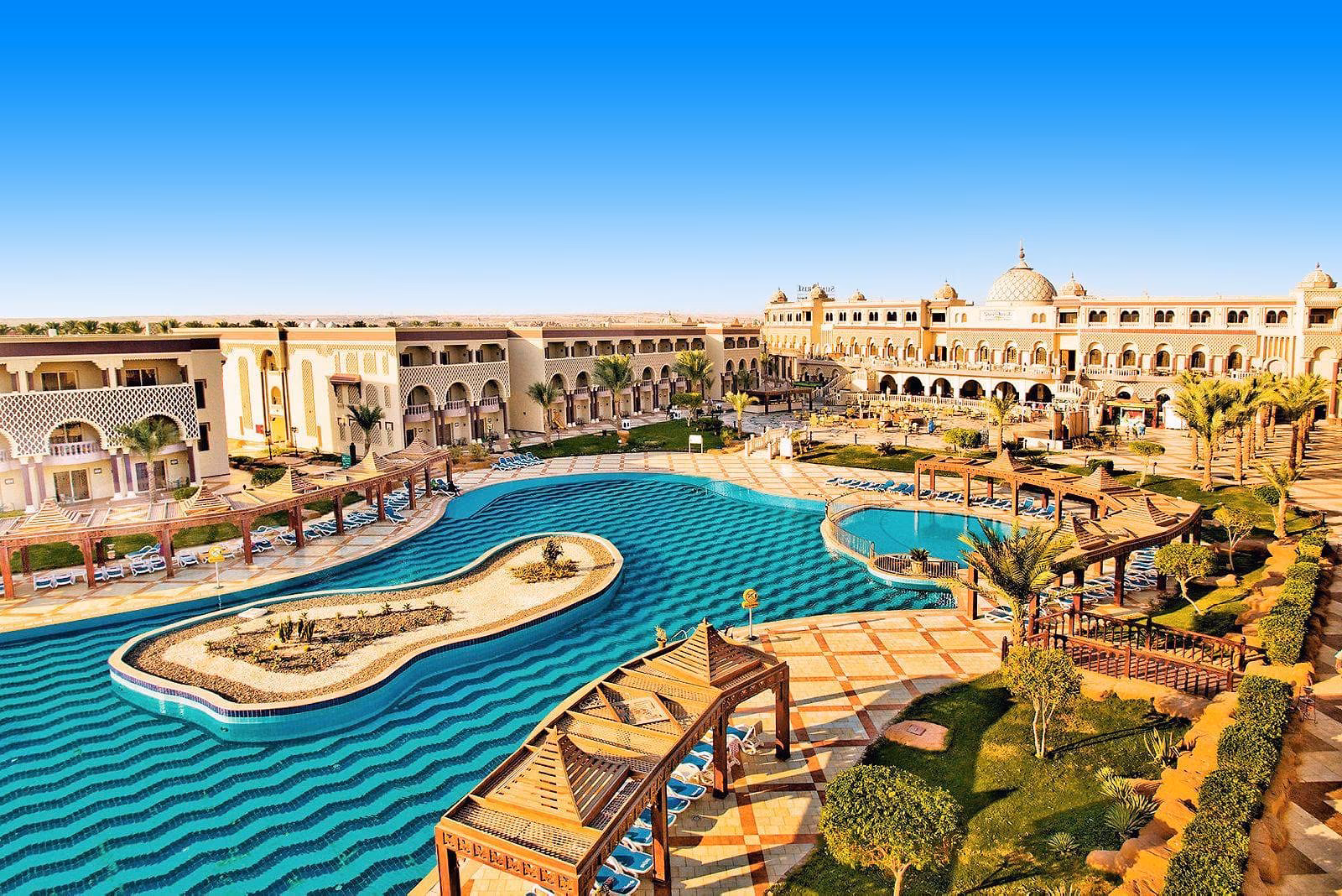 Het lagunezwembad van Sentido Mamlouk Palace in Hurghada met houten pergola's en het hoofdgebouw met koepels