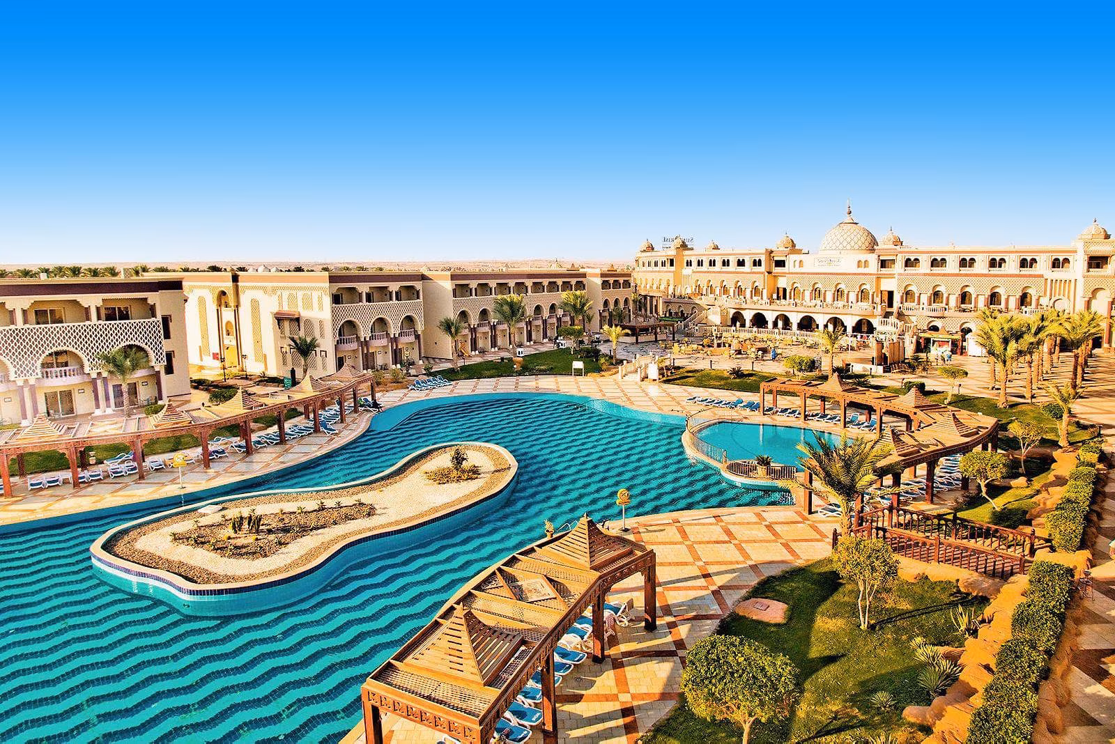 Het lagunezwembad van Sentido Mamlouk Palace in Hurghada met houten pergola's en het hoofdgebouw met koepels