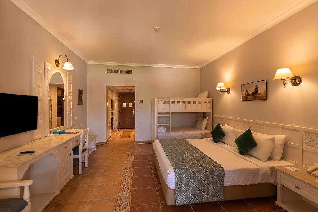 Familiekamer met een tweepersoonsbed met groene kussens, een wit stapelbed achterin en een bureau met flatscreen bij Sentido Mamlouk Palace Resort in Hurghada