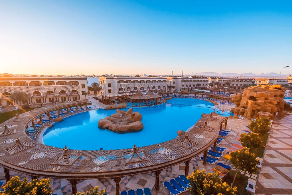 Zwembad met rotseiland bij zonsondergang in Sentido Mamlouk Palace in Hurghada, met bergen in de verte