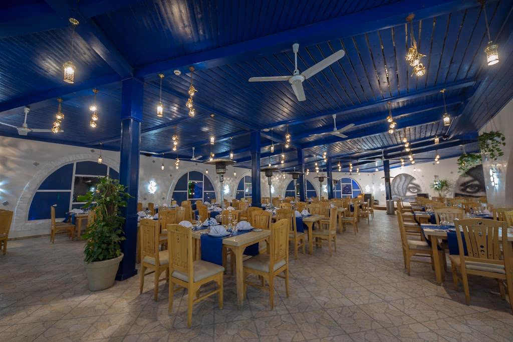 Overdekt restaurant met een blauw houten plafond, plafondventilatoren en hangende lantaarns bij Sentido Mamlouk Palace in Hurghada