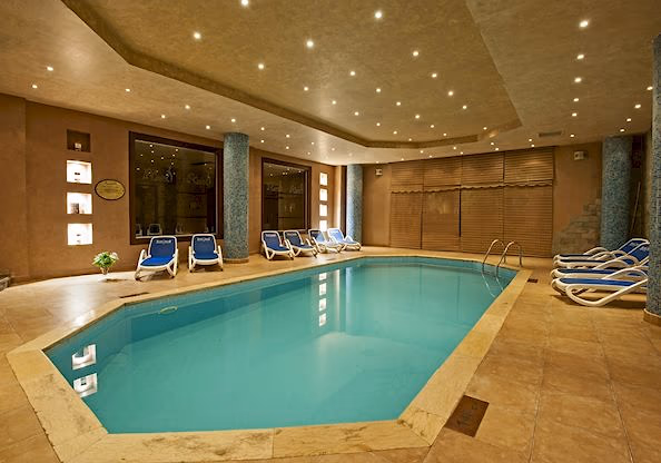 Overdekt zwembad met ligbedden, een sterrenhemelplafond en zuilen met mozaiek in de spa van Sentido Mamlouk Palace in Hurghada