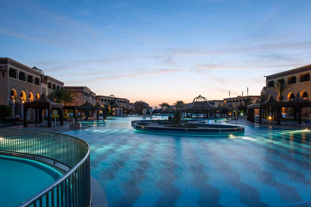 Verlicht lagunezwembad met eiland en pergola's in de schemering bij Sentido Mamlouk Palace in Hurghada